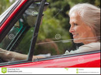 red mature smiling mature woman driving red convertible sunny day stock